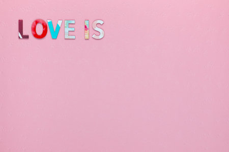 Inscription Love Is on pink textured background, aligned top leftの写真素材