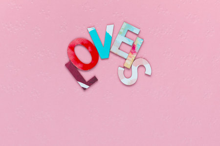 Close up of inscription Love Is, arranged in an arch shape, on pink textured backgroundの写真素材