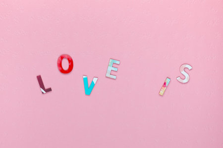 Inscription Love Is, randomly distributed on pink textured background, aligned in centerの写真素材