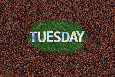 Tuesday written with colorful letters on artificial grass surrounded by roasted coffee beansの写真素材