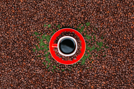 Coffee mug on red plate full of beans surrounded by many roasted coffee seedsの写真素材