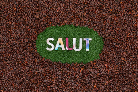 Word Salut with colorful letters on artificial grass surrounded by roasted coffee beansの写真素材
