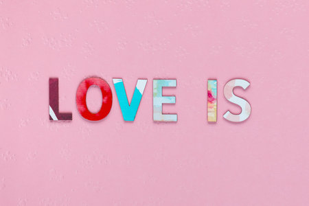 Inscription Love Is on pink textured background, shot close upの写真素材