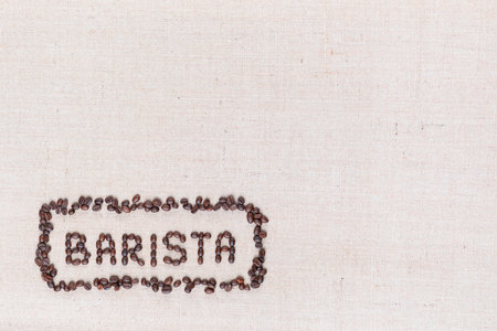 The word Barista inside a rectangle all made with coffee beans on creamy linea canvas, shot from above, aligned at the bottom left.の写真素材