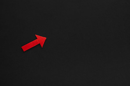 A red arrow pointing upwards on black background, shot from above.の写真素材