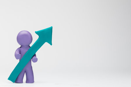 A man made from purple plasticine holding an arrow pointing upwards on white background, aligned to the left.の写真素材