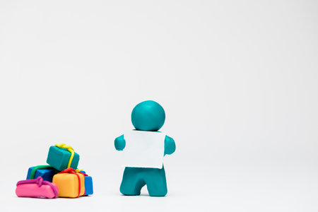 A man made from blue plasticine next to a big pile of gifts on white background , aligned in the center.の写真素材