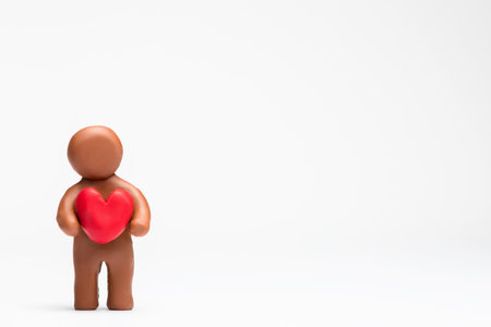A man made from plasticine holding a heart on white background, aligned to the left.の写真素材