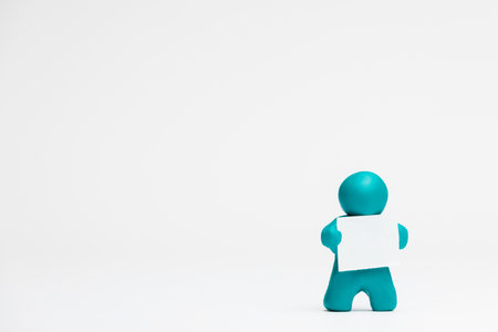 A man made from plasticine holding a blank sheet of paper on white background, aligned to the right.の写真素材