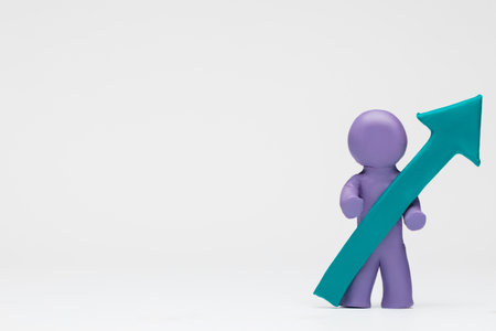A man made from purple plasticine holding an arrow pointing upwards on white background, aligned to the right.の写真素材