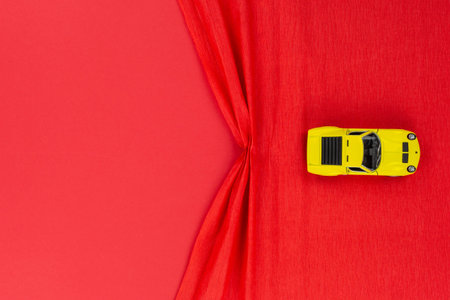 A yellow car figurine on a red wrinkled background, shot from above.の写真素材