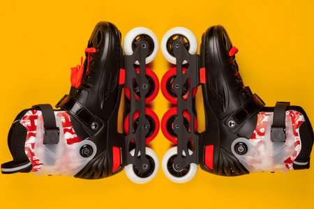 A pair of red roller skates on yellow background , shot from above.