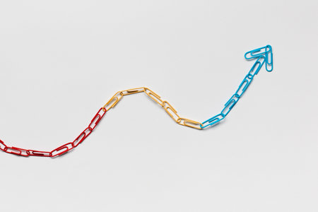 An arrow made from colored paperclips pointing upwards on a white background, shot from above.の写真素材
