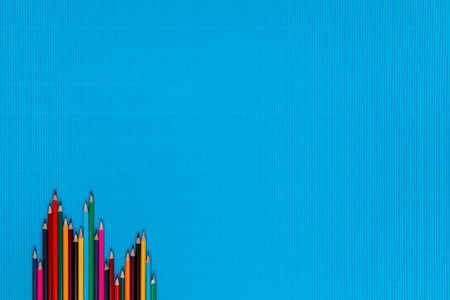 A bunch of colorful crayons of different sizes on a ocean blue background, shot from above, aligned at the bottom left.の写真素材