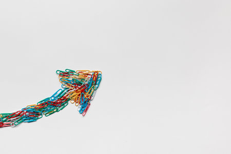 An arrow made from colored paperclips pointing upwards on a white background, shot from above.の写真素材