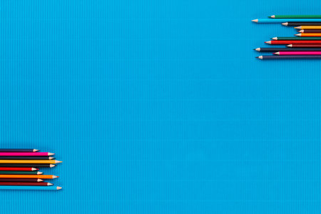 Two sets of colorful crayons in opposite corners on an ocean blue background, shot from above.の写真素材