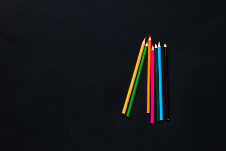 A bunch of colorful crayons on a black background, shot from above, centered.の写真素材