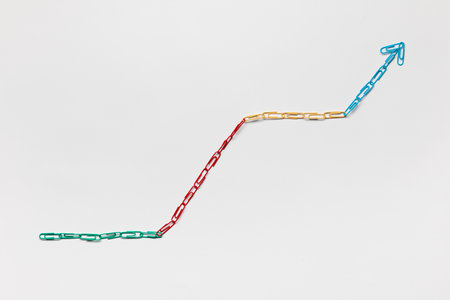 An arrow made from colored paperclips pointing upwards on a white background, shot from above.の写真素材
