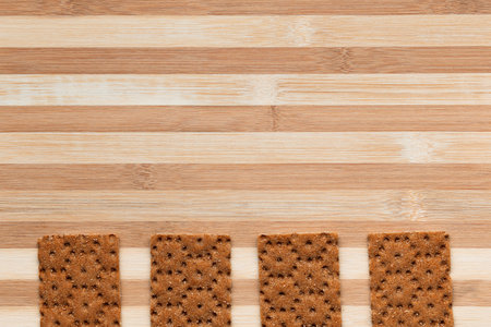 Slices of bread arranged close to one another on a brown table, shot from above.の写真素材