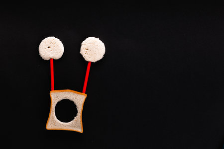 A face made with bread and crayons on a black background, shot from above, aligned at the bottom left.の写真素材