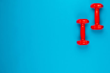 Two red dumbbells on blue background, shot from above, aligned at the top right.の写真素材