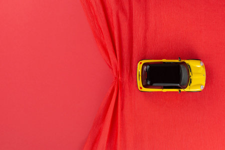A yellow car figurine on a red wrinkled background, shot from above.の写真素材