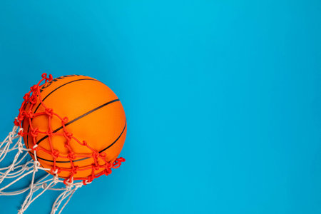 A ball passing through a basket, on blue background, shot from above, aligned at the top left.の写真素材
