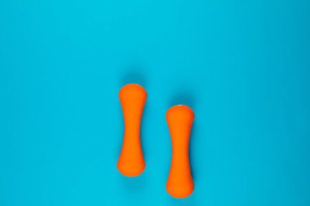 Two orange dumbbells on blue background, shot from above, aligned at the bottom..の写真素材