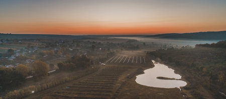 A beautiful shot of a lake near surrounded by fields and trees in the evening, aerial view.