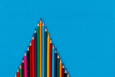 A bunch of colorful crayons forming a triangle on an ocean blue background, shot from above, arranged in the center.の写真素材