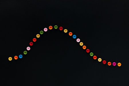 A wave made from colored buttons on a black background, shot from above.の写真素材