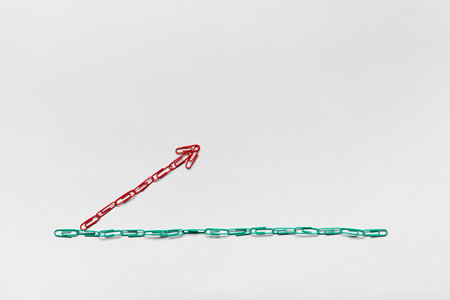 An arrow made from colored paperclips pointing upwards on a white background, shot from above.の写真素材