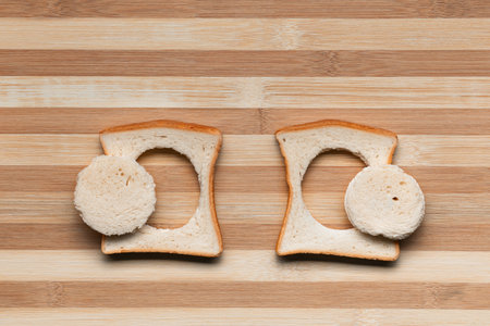 Two slices of bread with their centers cut on a brown table, shot from above.の写真素材