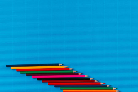 A bunch of colorful crayons spread diagonally on an ocean blue background , shot from above , aligned from left to bottom right.の写真素材
