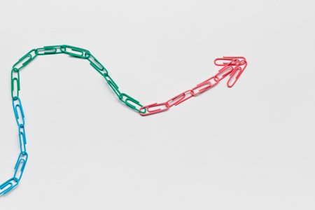 An arrow made from colored paperclips pointing upwards on a white background, shot from above.の写真素材