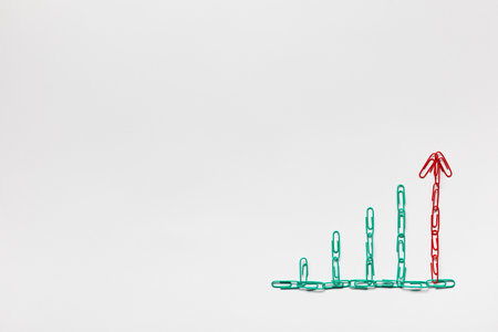 A graph moving upwards made with green and red paperclips with buttons on top on white background, shot from above.の写真素材