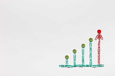 A graph moving upwards made with green and red paperclips with buttons on top on white background, shot from above.の写真素材