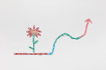 A flower growing on an arrow pointing upwards all made with colored paperclips,shot from above.の写真素材