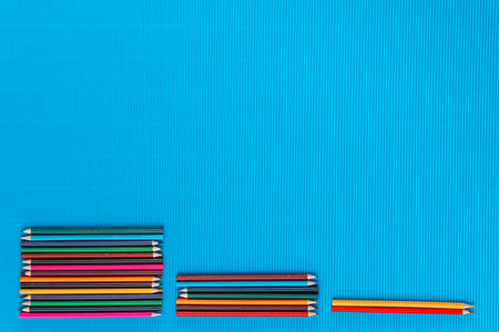 A bunch of colorful crayons forming three columns on an ocean blue background, shot from above.の写真素材