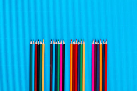 A bunch of colorful crayons forming four columns on an ocean blue background, shot from above, closeup.の写真素材