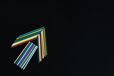 An arrow made with colored counting sticks on a black background , shot from above arranged at the bottom left, closeup.の写真素材