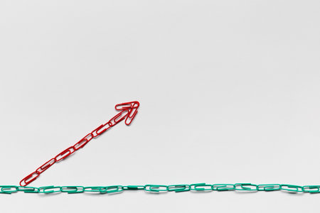 An arrow made from colored paperclips pointing upwards on a white background, shot from above, closeup.の写真素材