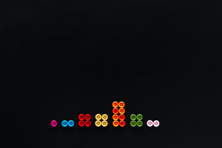 Buttons sorted by color in groups on a black background, shot from above.の写真素材