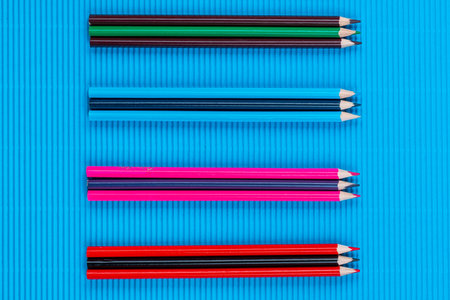 A bunch of colorful crayons of different sizes arranged randomly on a blue background , shot from above, arranged in the center, closeup.の写真素材