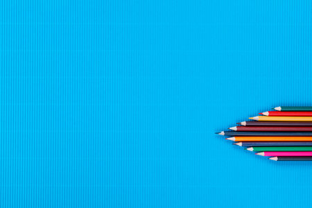 A bunch of colorful crayons of different sizes on a ocean blue background, shot from above , arranged at the bottom right.の写真素材