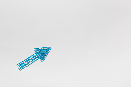 An arrow made from colored paperclips pointing upwards on a white background, shot from above.の写真素材
