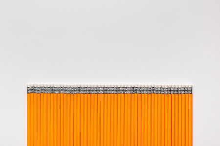A bunch of pencils aligned in a straight line on white background , shot from above.の写真素材