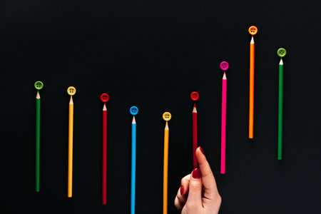 Crayons with buttons of the same color forming a wave on black background, shot from above.の写真素材