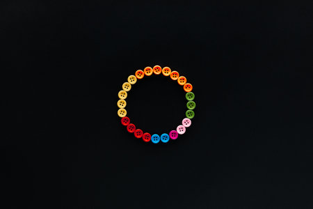 A circle made from colored buttons on black background, shot from above , arranged in the center.の写真素材