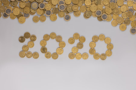 A heap and 2020 all made with golden coins, shot from above, white background.